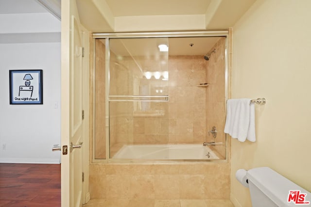 bathroom with hardwood / wood-style flooring, toilet, and tiled shower / bath