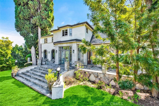 rear view of property featuring a patio, a lawn, and french doors