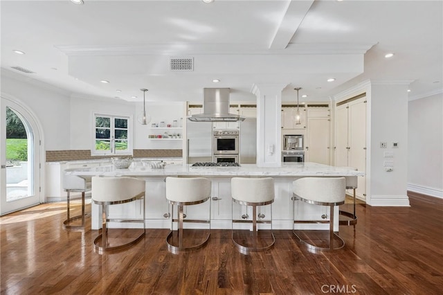 kitchen with a large island, wall chimney exhaust hood, a kitchen bar, and pendant lighting