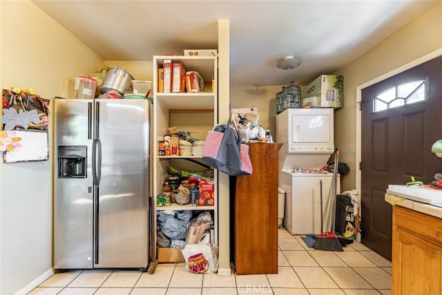 kitchen with stacked washer / dryer, stainless steel fridge, and light tile patterned floors