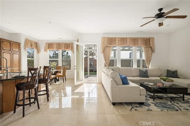 living room featuring ceiling fan and a healthy amount of sunlight