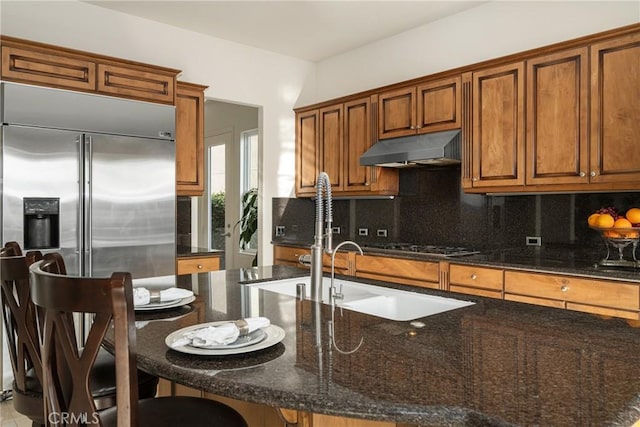 kitchen featuring dark stone countertops, a breakfast bar, decorative backsplash, sink, and stainless steel appliances