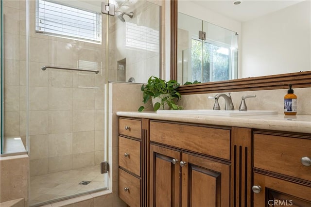 bathroom with a shower with shower door and vanity