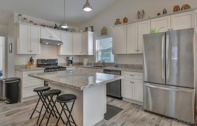 kitchen featuring lofted ceiling, a kitchen island, light wood-type flooring, pendant lighting, and stainless steel appliances