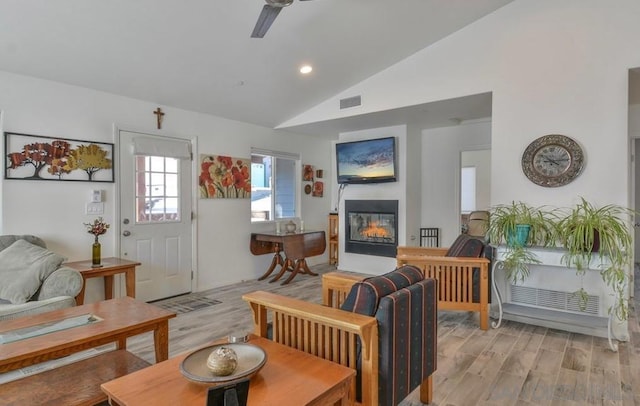 living room with ceiling fan, light wood-type flooring, and vaulted ceiling