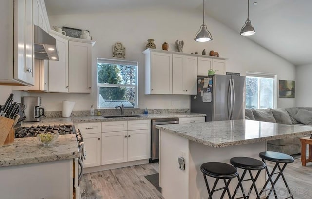 kitchen featuring appliances with stainless steel finishes, sink, white cabinetry, lofted ceiling, and range hood