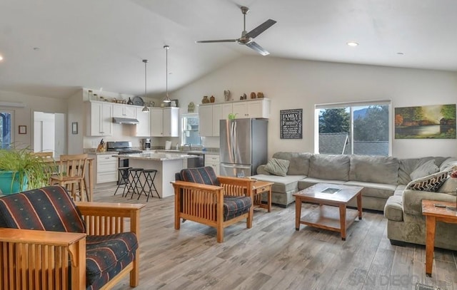 living room featuring sink, light hardwood / wood-style floors, lofted ceiling, and ceiling fan