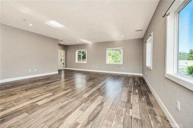 unfurnished room with a healthy amount of sunlight and hardwood / wood-style floors