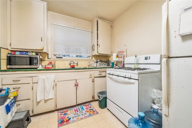 kitchen featuring backsplash, white appliances, and sink