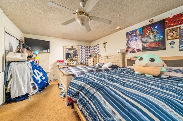 bedroom with ceiling fan, carpet floors, and a textured ceiling