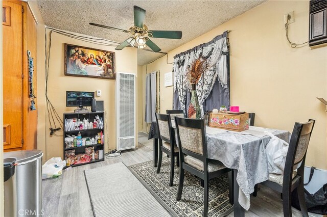 dining room with ceiling fan, a textured ceiling, and light wood-type flooring