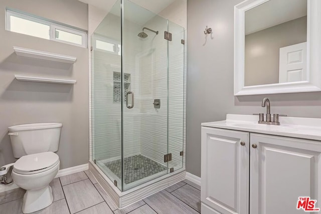 bathroom with vanity, a shower with shower door, and toilet