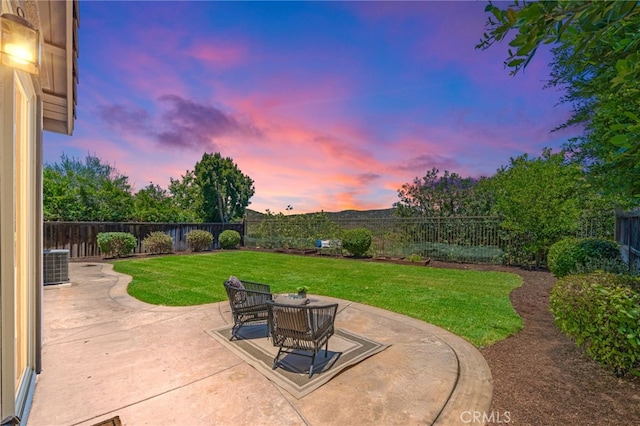 patio terrace at dusk featuring central AC unit and a lawn