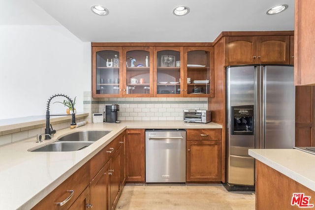 kitchen featuring tasteful backsplash, stainless steel appliances, sink, and light wood-type flooring