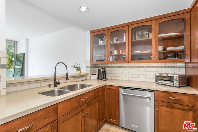 kitchen with light hardwood / wood-style flooring, kitchen peninsula, sink, stainless steel dishwasher, and tasteful backsplash