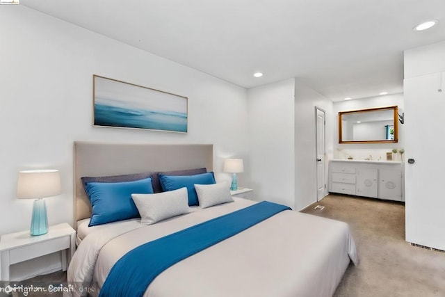 bedroom featuring ensuite bathroom and light colored carpet