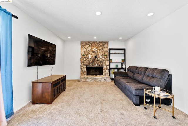 living room featuring a textured ceiling, light colored carpet, and a stone fireplace