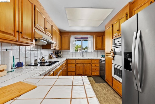 kitchen featuring tile countertops, decorative backsplash, sink, and stainless steel appliances