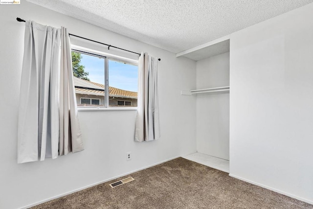 carpeted empty room featuring a textured ceiling