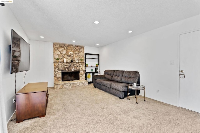 carpeted living room with a stone fireplace and a textured ceiling