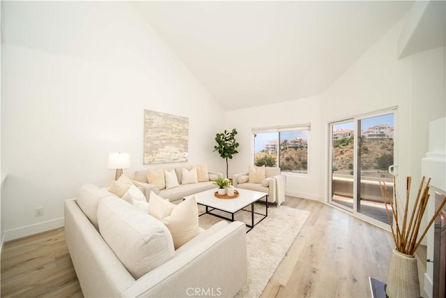 living room with light hardwood / wood-style floors and high vaulted ceiling