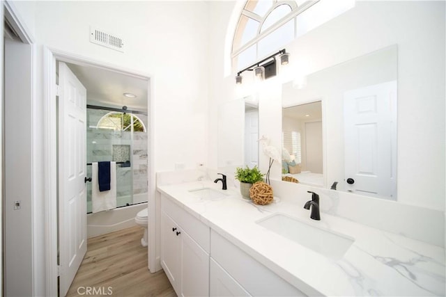 full bathroom with shower / bath combination with glass door, hardwood / wood-style floors, vanity, and toilet