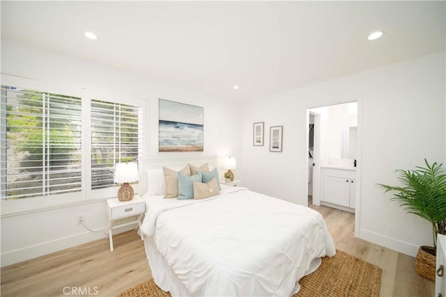 bedroom with connected bathroom and light hardwood / wood-style flooring