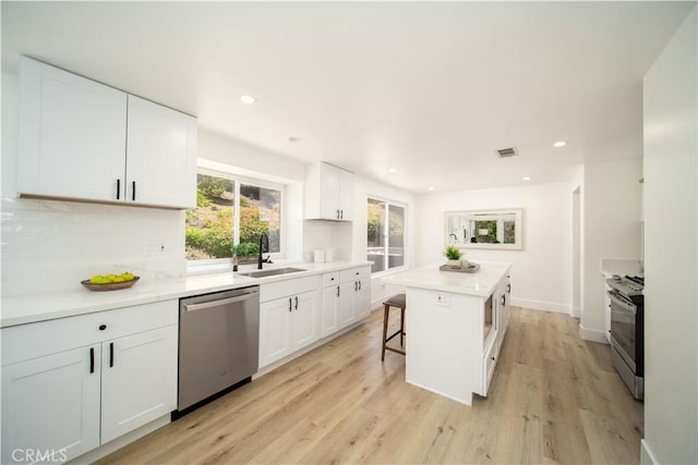 kitchen with white cabinets, appliances with stainless steel finishes, a center island, and sink