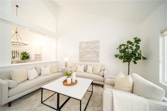 living room with light colored carpet, high vaulted ceiling, and a chandelier