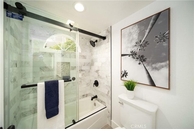 bathroom with toilet and shower / bath combination with glass door