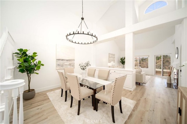 dining area with light hardwood / wood-style flooring, high vaulted ceiling, and a chandelier