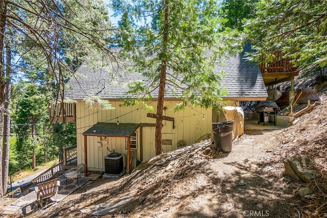 view of side of home with cooling unit and a storage shed