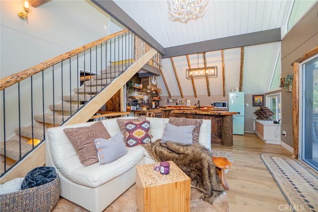 living room featuring lofted ceiling with beams, sink, a notable chandelier, and light hardwood / wood-style flooring