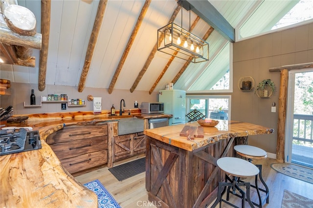 kitchen featuring butcher block counters, lofted ceiling with beams, stainless steel appliances, and light wood-type flooring