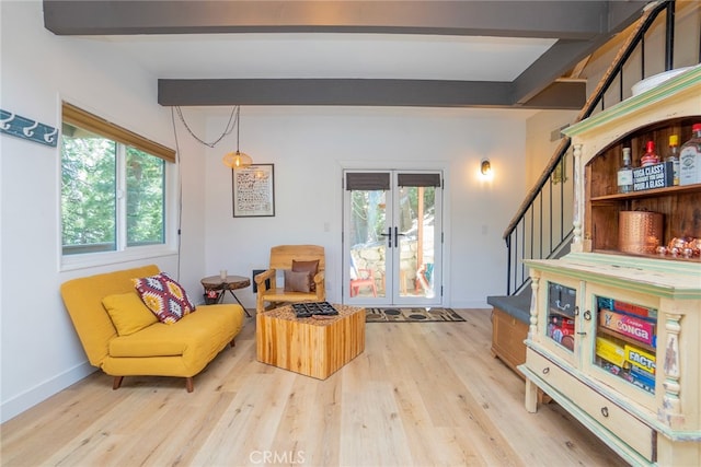 sitting room with beamed ceiling, french doors, and light hardwood / wood-style flooring