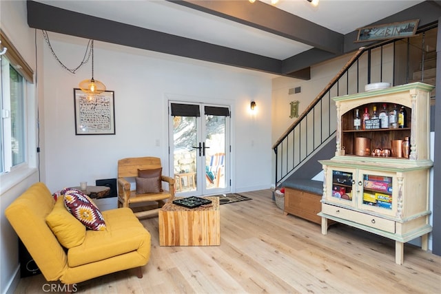 living room featuring french doors, beamed ceiling, and light wood-type flooring