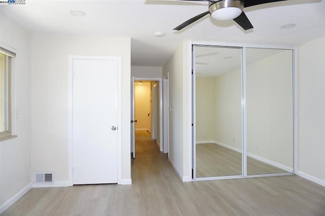 unfurnished bedroom with light hardwood / wood-style floors, ceiling fan, and a closet