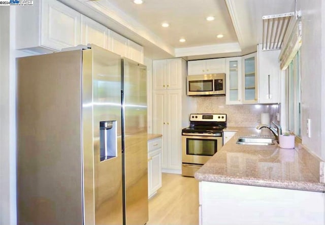 kitchen with appliances with stainless steel finishes, white cabinetry, and sink