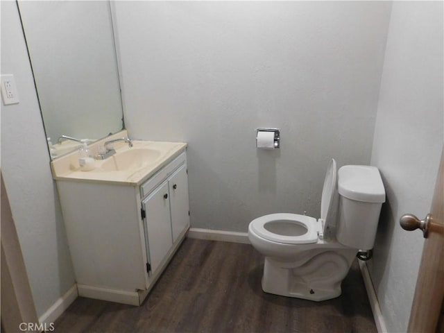 bathroom featuring toilet, vanity, baseboards, and wood finished floors