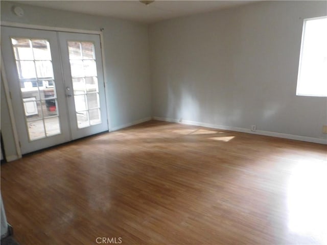 empty room with light wood-style floors, french doors, and baseboards