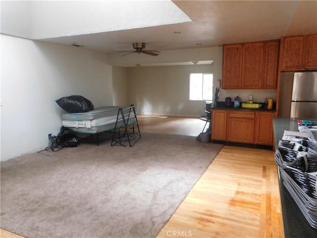 kitchen with brown cabinets, dark countertops, open floor plan, and freestanding refrigerator