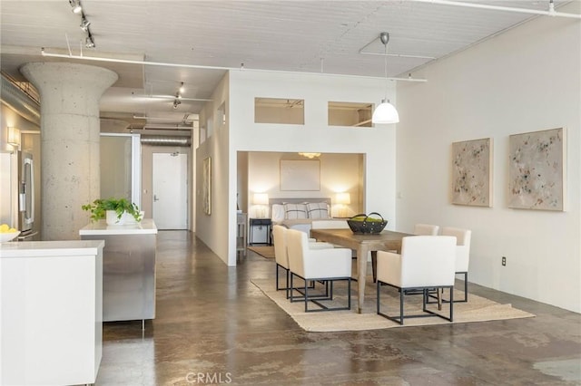 dining room with a high ceiling and track lighting