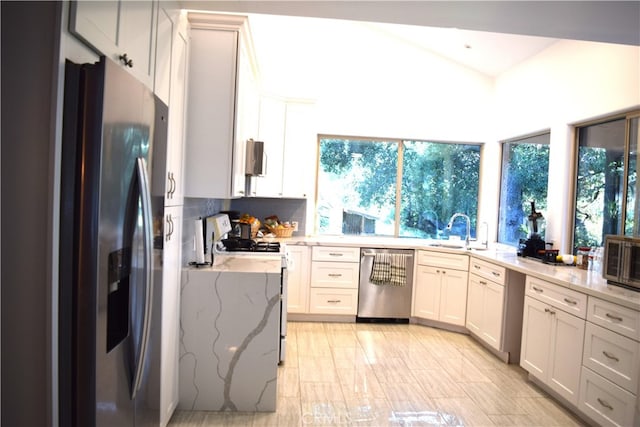 kitchen with decorative backsplash, light stone counters, appliances with stainless steel finishes, white cabinetry, and sink