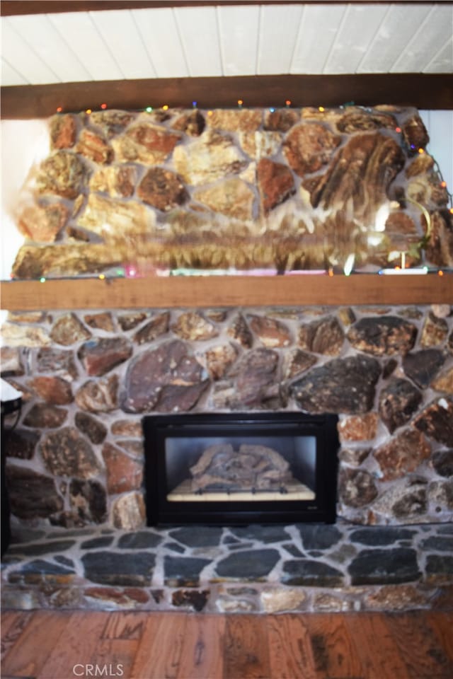 interior details featuring beam ceiling, hardwood / wood-style flooring, wooden ceiling, and a fireplace