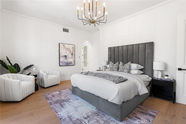 bedroom featuring hardwood / wood-style floors, a notable chandelier, and crown molding