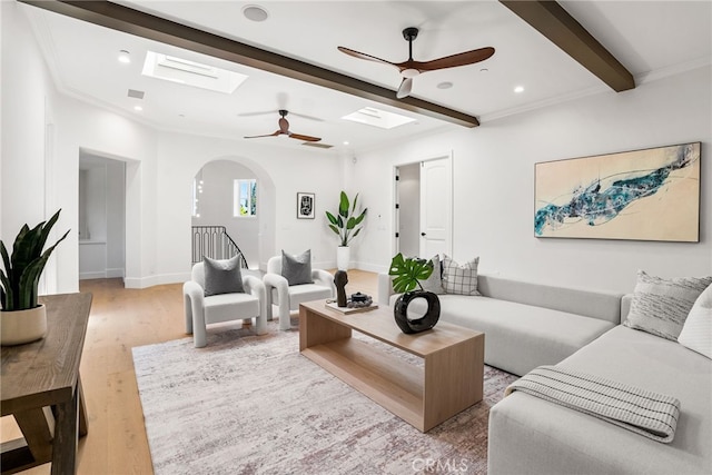 living room featuring hardwood / wood-style floors, ceiling fan, ornamental molding, and beam ceiling