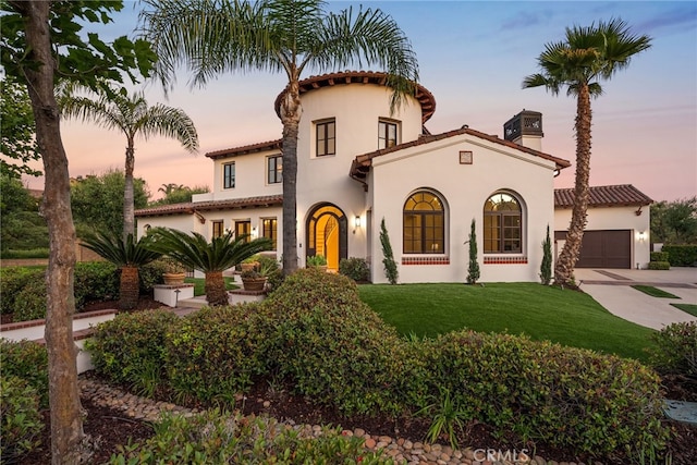 mediterranean / spanish-style house with a yard and a garage