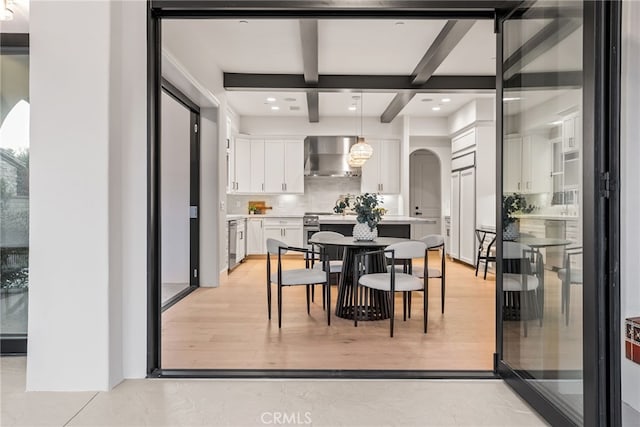 dining area with beamed ceiling, coffered ceiling, and light hardwood / wood-style flooring