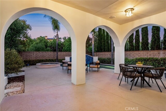 patio terrace at dusk featuring an in ground hot tub