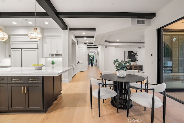 kitchen featuring pendant lighting, light hardwood / wood-style floors, light stone counters, and white cabinetry